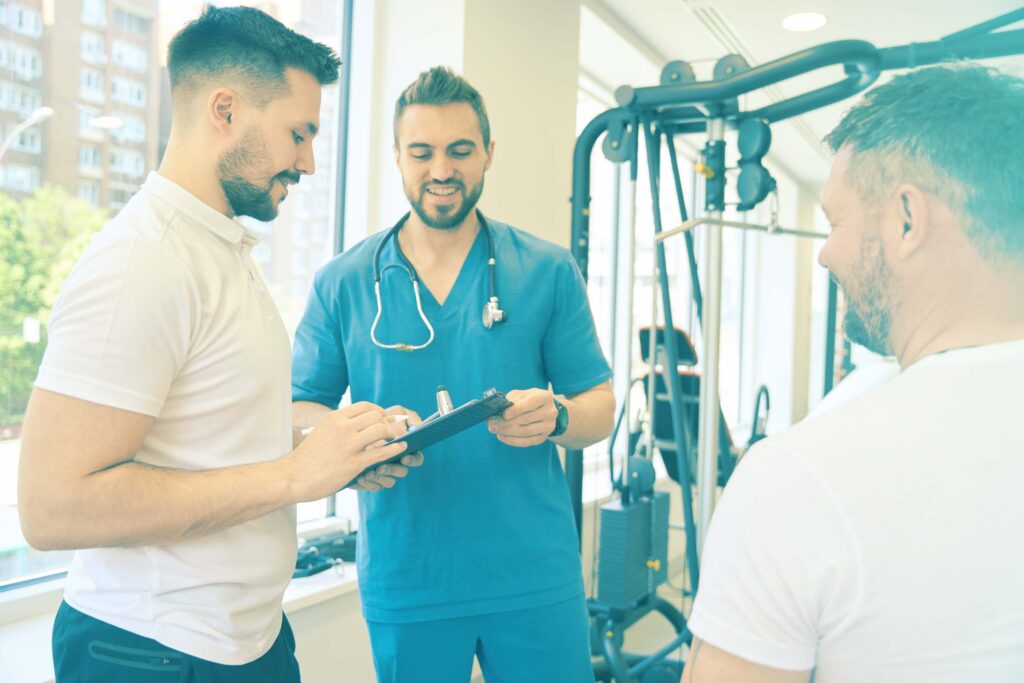 Deux hommes souriants en rencontre avec un ergothérapeute dans un centre d'ergothérapie.